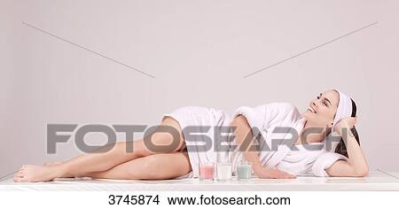 Smiling young woman in a bathrobe, lying, looking up View Large Photo Image Picture - Smiling young woman in a bathrobe, lying, looking up. Fotosearch