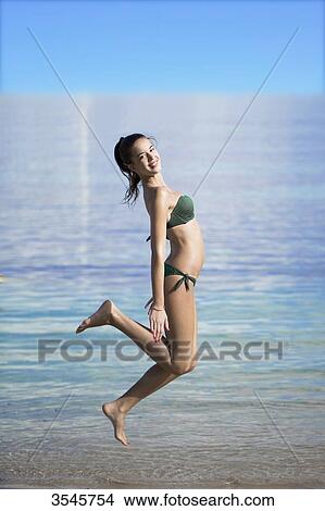 Teenage girl making a leap to the seaside View Large Photo Image Picture - Teenage girl making a leap to the seaside. Fotosearch