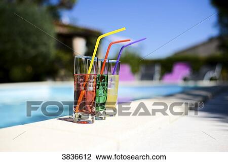 Three tropical colorful drink cocktail with straw on the poolside of resort swimming pool with nobody. View Large Photo Image Stock Image - Three tropical colorful drink cocktail with straw on the poolside of resort swimming pool with nobody.. Fotosearch