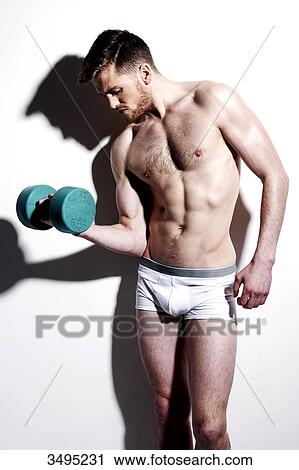 Topless man, against a white wall; wearing white pants, serious, hard shadow on the wall, with a weight in his hand, looking down View Large Photo Image Stock Image - Topless man, against a white wall; wearing white pants, serious, hard shadow on the wall, with a weight in his hand, looking down. Fotosearch