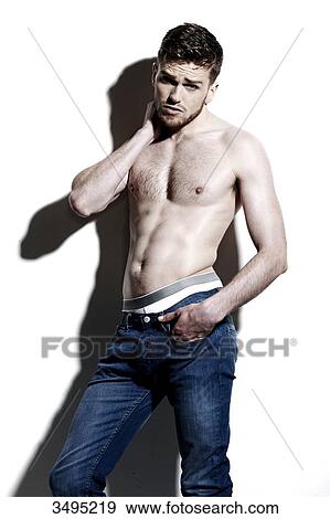 Topless man against a white wall; wearing jeans, serious, poised, hand in the pocket, hard shadow on the wall, looking at camera, one hand behind his neck View Large Photo Image Stock Photo - Topless man against a white wall; wearing jeans, serious, poised, hand in the pocket, hard shadow on the wall, looking at camera, one hand behind his neck. Fotosearch