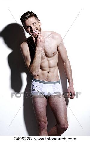 Topless man, against a white wall; wearing white pants, hard shadow on the wall, looking at camera, poised, smiling, one hand on his chin View Large Photo Image Stock Photo - Topless man, against a white wall; wearing white pants, hard shadow on the wall, looking at camera, poised, smiling, one hand on his chin. Fotosearch