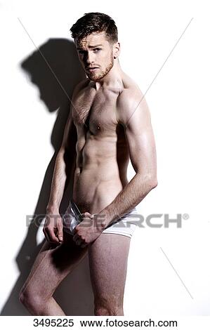 Topless man, against a white wall; wearing white pants, serious, poised, hard shadow on the wall, looking at camera, thumb in his pants. View Large Photo Image Stock Photography - Topless man, against a white wall; wearing white pants, serious, poised, hard shadow on the wall, looking at camera, thumb in his pants.. Fotosearch