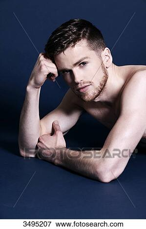 Topless man, dark blue background; lying on the floor, serious, holding his head with his fist, seducing, looking at the camera View Large Photo Image Stock Photo - Topless man, dark blue background; lying on the floor, serious, holding his head with his fist, seducing, looking at the camera. Fotosearch