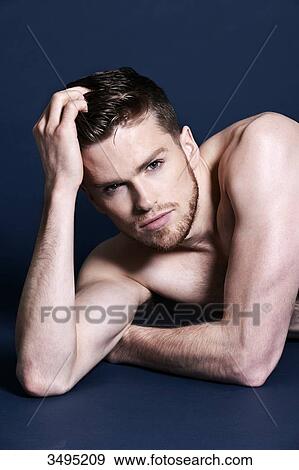 Topless man, dark blue background; lying on the floor, serious, one hand in his hair, looking at the camera View Large Photo Image Stock Photo - Topless man, dark blue background; lying on the floor, serious, one hand in his hair, looking at the camera. Fotosearch
