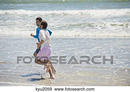 Two men running on the beach View Large Photo Image Stock Photo - Two men running on the beach. Fotosearch