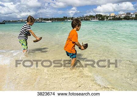 Two young boys, 5 and 7 years old, playing with small boat in coco ont he beach, Gosier island, Guadeloupe, France View Large Photo Image Picture - Two young boys, 5 and 7 years old, playing with small boat in coco ont he beach, Gosier island, Guadeloupe, France. Fotosearch