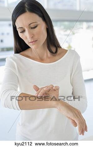 Stock Image - Woman applying ointment on her arm. Fotosearch