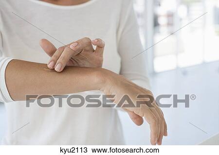 Stock Image - Woman applying ointment on her arm. Fotosearch