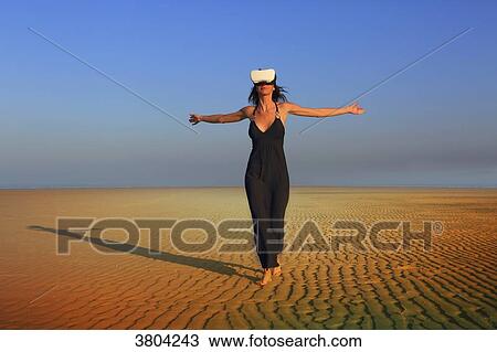 Stock Image - Woman at beach. Virtual Reality Headset. Fotosearch