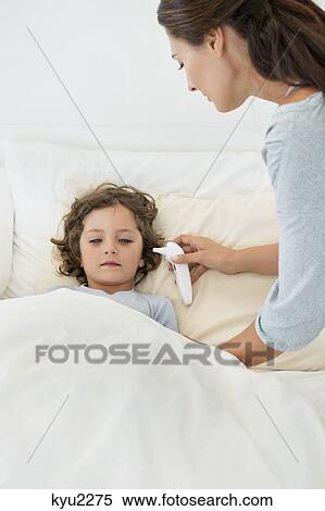 Stock Photography - Woman checking fever of her son with a thermometer. Fotosearch