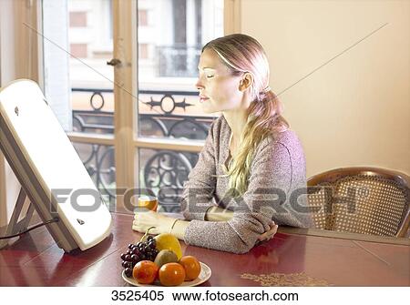 Stock Photography - Woman doing a session of light therapy. Fotosearch