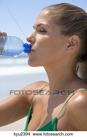 Woman drinking water from a bottle View Large Photo Image Picture - Woman drinking water from a bottle. Fotosearch
