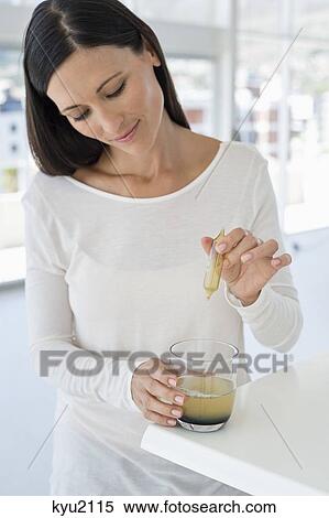 Stock Photography - Woman dropping liquid medicine into water. Fotosearch