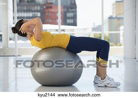 Woman exercising on a fitness ball in a gym View Large Photo Image Picture - Woman exercising on a fitness ball in a gym. Fotosearch