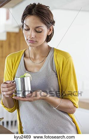 Woman holding a cup of herbal tea in the kitchen View Large Photo Image Stock Photo - Woman holding a cup of herbal tea in the kitchen. Fotosearch