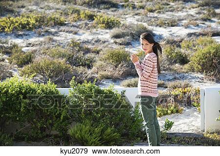 Stock Photo - Woman holding a flower in vegetation. Fotosearch