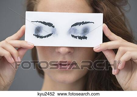 Woman holding a paper with false eyes in front of her face View Large Photo Image Stock Image - Woman holding a paper with false eyes in front of her face. Fotosearch