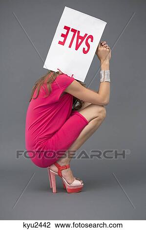 Stock Image - Woman holding a shopping bag over her face. Fotosearch