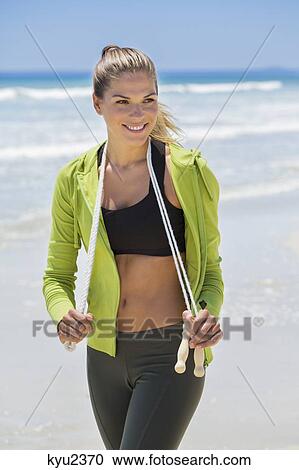 Stock Image - Woman holding a skipping rope on the beach. Fotosearch