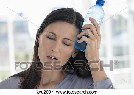 Woman holding a water bottle on her forehead View Large Photo Image Stock Photo - Woman holding a water bottle on her forehead. Fotosearch