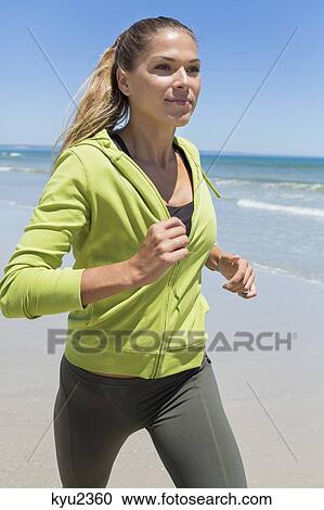Stock Image - Woman jogging on the beach. Fotosearch