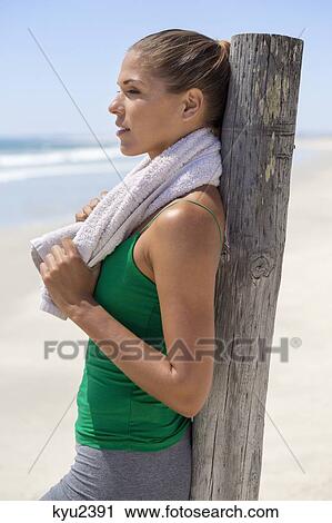 Woman leaning against a wooden post on the beach View Large Photo Image Stock Image - Woman leaning against a wooden post on the beach. Fotosearch