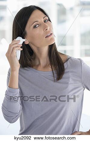 Stock Image - Woman measuring her temperature with a digital thermometer. Fotosearch