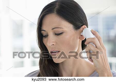 Stock Image - Woman measuring her temperature with a digital thermometer. Fotosearch