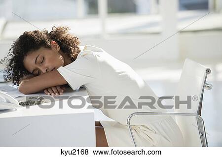 Stock Photo - Woman napping with her head resting on desk. Fotosearch