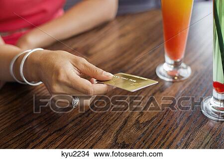Picture - Woman paying with a credit card on a table in a restaurant. Fotosearch