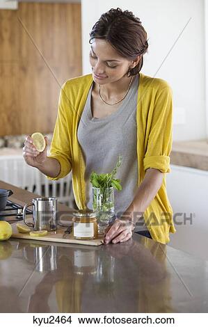 Picture - Woman preparing herbal tea in the kitchen. Fotosearch