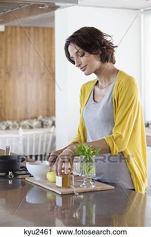 Stock Image - Woman preparing herbal tea in the kitchen. Fotosearch