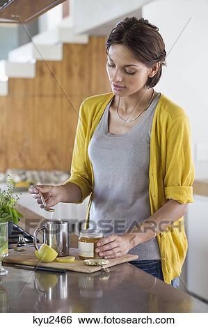 Stock Photograph - Woman preparing herbal tea in the kitchen. Fotosearch