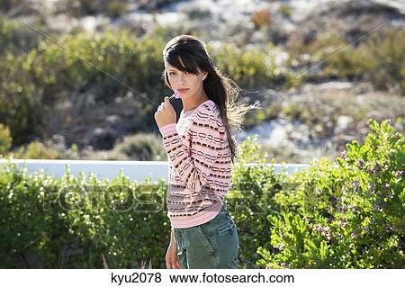 Woman smelling a flower in vegetation View Large Photo Image Stock Photo - Woman smelling a flower in vegetation. Fotosearch