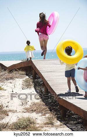 Woman walking with her children on a boardwalk on the beach View Large Photo Image Stock Image - Woman walking with her children on a boardwalk on the beach. Fotosearch