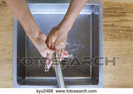 Stock Photo - Woman washing her hands in the kitchen. Fotosearch