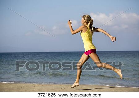 Stock Photography - Young blond woman running on the beach. Fotosearch