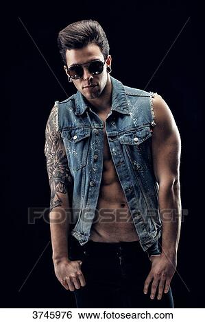 Young man in jeans jacket, hands in pockets, looking at the camera View Large Photo Image Stock Photograph - Young man in jeans jacket, hands in pockets, looking at the camera. Fotosearch