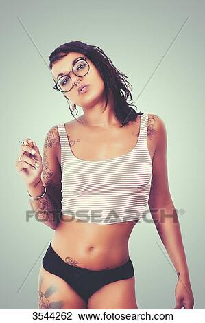 Young tattooed woman posing with a cigarette View Large Photo Image Stock Image - Young tattooed woman posing with a cigarette. Fotosearch
