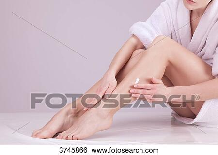 Young woman applying cream on her legs View Large Photo Image Stock Photograph - Young woman applying cream on her legs. Fotosearch