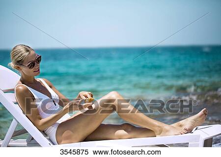 Young woman applying sun cream on a lounger View Large Photo Image Stock Photography - Young woman applying sun cream on a lounger. Fotosearch
