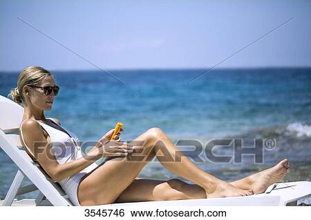 Young woman applying sun cream View Large Photo Image Stock Photograph - Young woman applying sun cream. Fotosearch