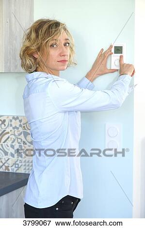 Young woman at home tuning temperature View Large Photo Image Stock Photo - Young woman at home tuning temperature. Fotosearch