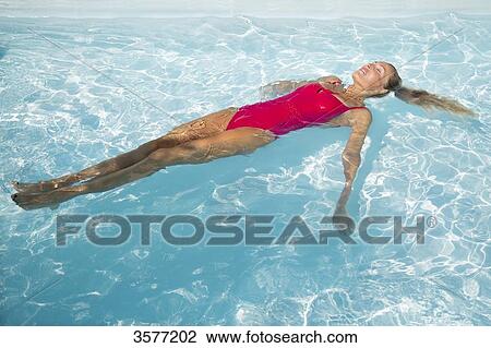 Young woman floating in a pool View Large Photo Image Stock Image - Young woman floating in a pool. Fotosearch