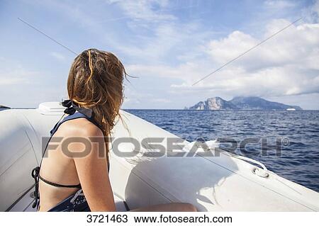 Young woman from behind, contemplates the island of Capri, in front of a boat View Large Photo Image Stock Image - Young woman from behind, contemplates the island of Capri, in front of a boat. Fotosearch
