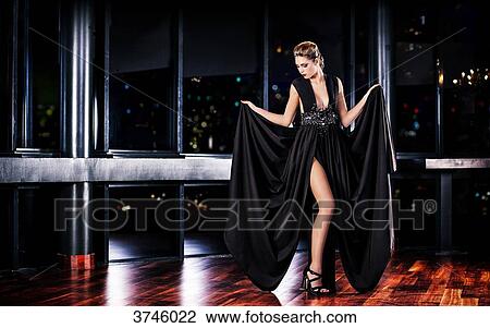 Young woman holds her evening dress with both hands, standing, head in profile, looking down View Large Photo Image Stock Image - Young woman holds her evening dress with both hands, standing, head in profile, looking down. Fotosearch