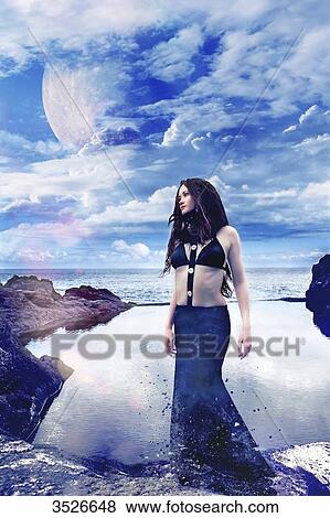 Young woman in black dress, standing, by the sea View Large Photo Image Stock Photo - Young woman in black dress, standing, by the sea. Fotosearch