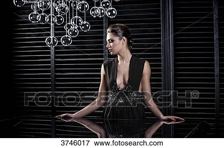 Stock Photo - Young woman in evening dress, profile, standing, looking to the side. Fotosearch