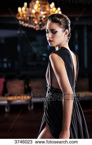 Young woman in evening dress standing in profile, looking down View Large Photo Image Stock Image - Young woman in evening dress standing in profile, looking down. Fotosearch